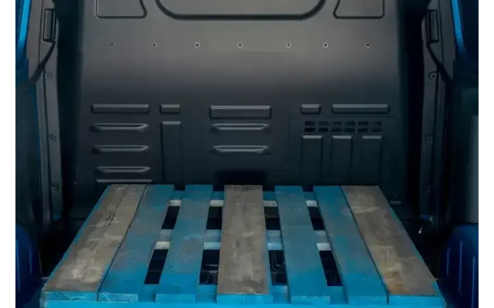 Interior view of a blue Ford Transit Courier with a wooden pallet.