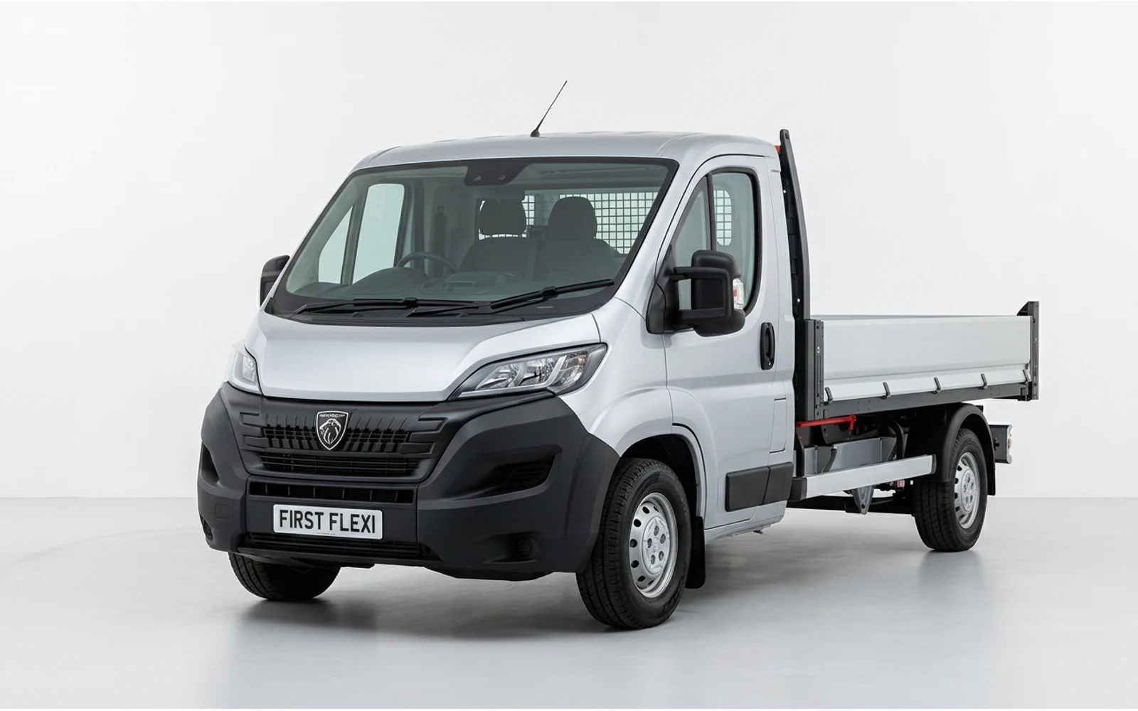 Silver Peugeot Boxer flatbed truck, viewed from the front three-quarter angle.