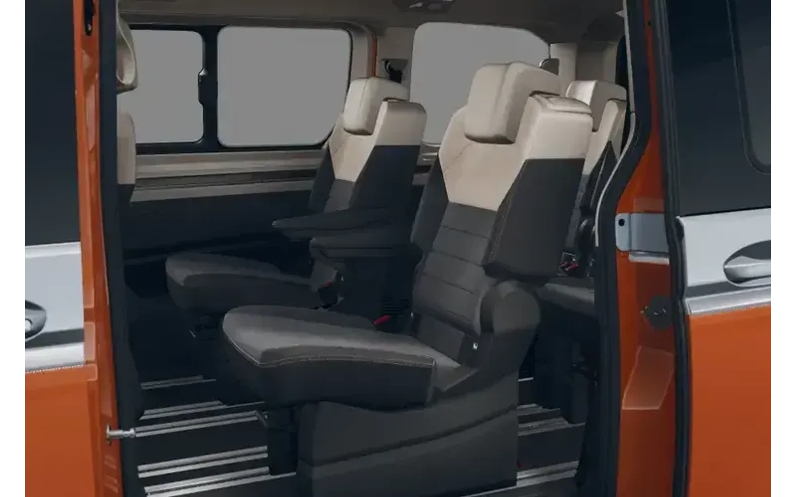 Interior of an orange Volkswagen Multivan showing two rows of grey and beige seats from the side.