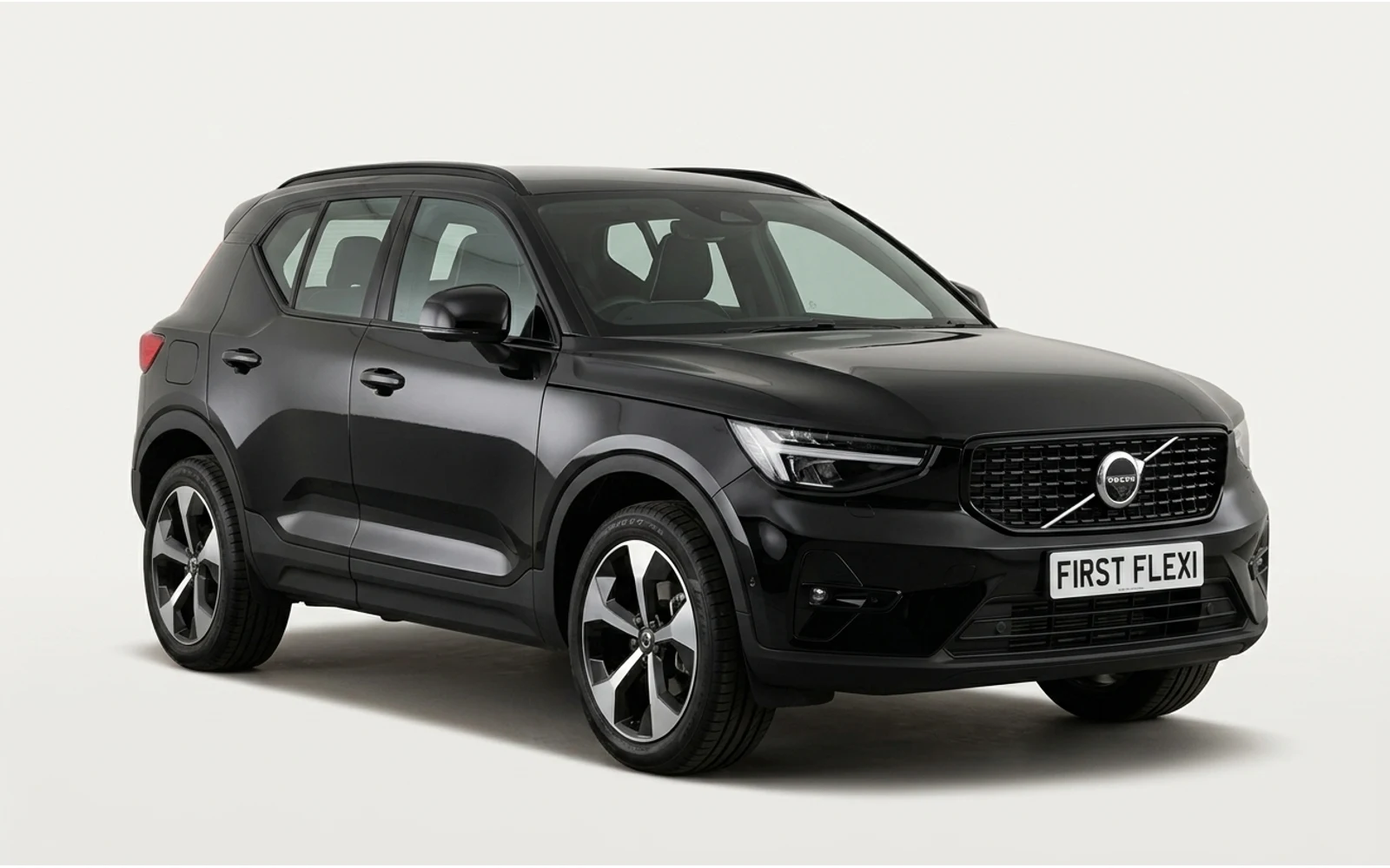 A black Volvo XC40 is shown from the front-right angle against a black background.